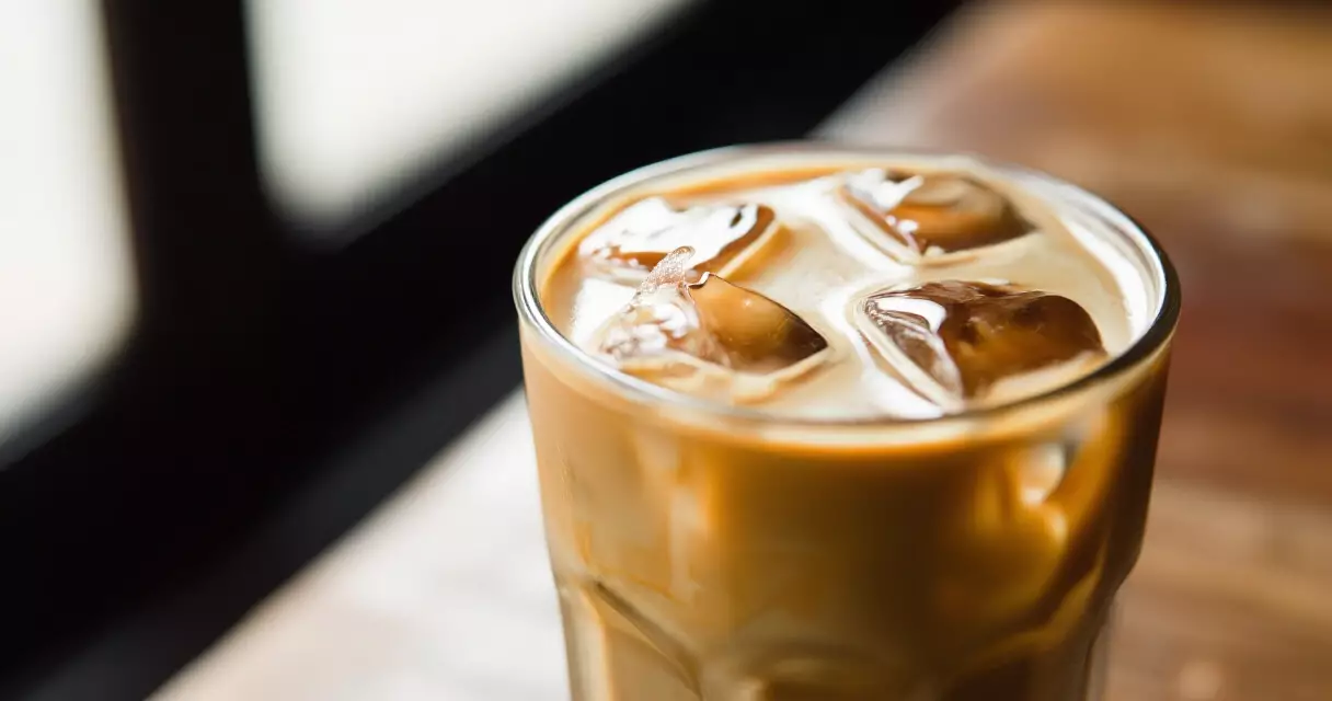 ភេសជ្ជៈ Palm Sugar Latte ត្រជាក់ក្នុងកែវថ្លានៅលើតុឈើ