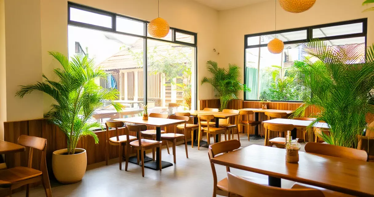 បរិយាកាសខាងក្នុងហាង Park Caf&eacute; ភ្នំពេញ ដែលមានដើមឈើ និងពន្លឺថ្ងៃ