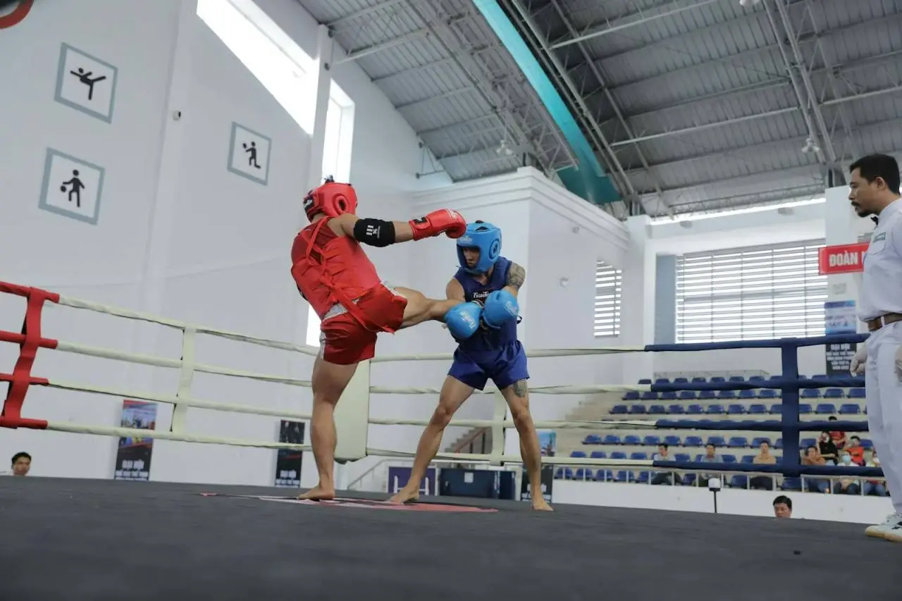 Two kickboxers in action during a competitive match in an indoor ring.