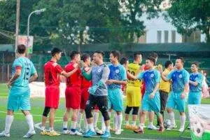 Two soccer teams shake hands on the field in Hanoi, showcasing sportsmanship.