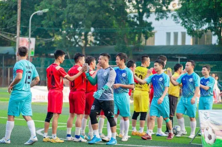 Two soccer teams shake hands on the field in Hanoi, showcasing sportsmanship.