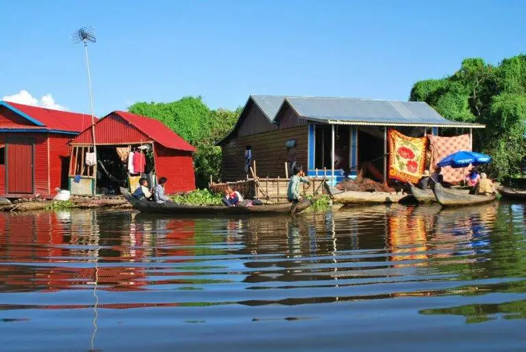 Vibrant floating village scene with locals in wooden boats on a sunny day.