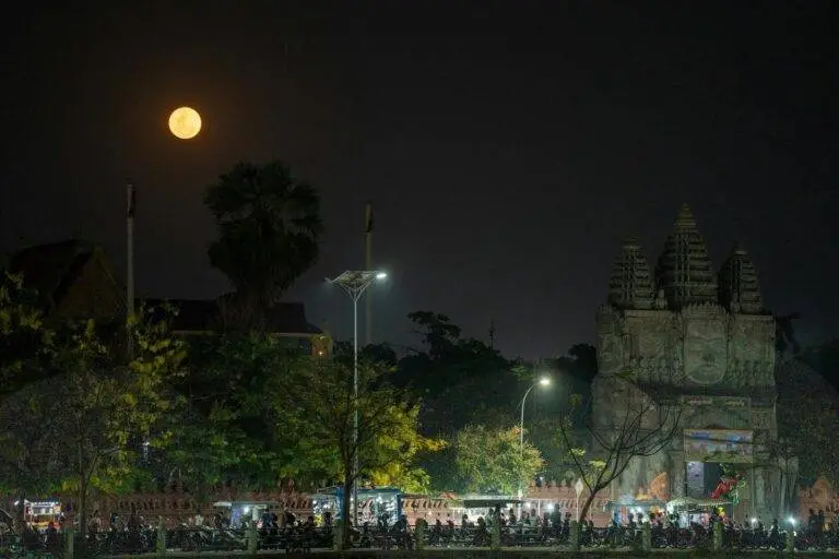 A serene night view of a temple in Battambang, Cambodia, under a full moon.